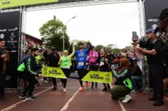 Hugo cruzando a linha de chegada da maratona 366 ao lado de sua família