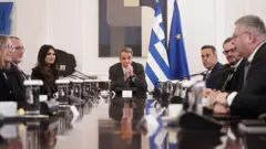 Yunanistan Başbakanı Kiryakos Miçotakis, Yunanistan Devleti ile Chevron-Helleniq Energy temsilcileri ile bir masada toplantı sırasında, arkada Yunan bayrağı ve AB bayrağı görülüyor