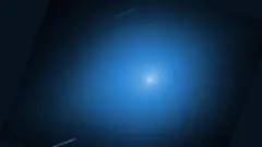 Imagen del cometa 3I/ATLAS en la que se ve en el centro un punto brillante con una estela en un fondo azul claro