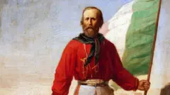 Pintura mostra Giuseppe Garibaldi vestindo uma camisa vermelha, usando um lenço negro no pescoço e empunhando uma bandeira da Itália