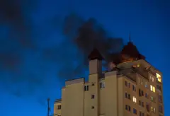 Дим здіймається після того, як уламки перехопленого російського дрона впали на дах багатоповерхового житлового будинку в Києві, Україна, 12 травня 2026 року.