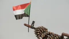 ጠመንጃ ላይ የተንጠለጠለ የሱዳን ባንዲራ