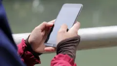 Muslim Girl wearing religious dress and hijab using mobile phone at public park outdoor