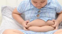 un niño con sobrepeso sosteniéndose el abdomen