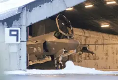 Parte delantera de un caza F-35 visto en el interior de un hangar. Hay nieve en el suelo y parece haberla también sobre el techo del hangar.