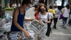 香港某報攤前一位年輕女性在購買《蘋果日報》（18/6/2011）