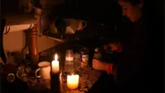 Жінка запалює свічки після того, як світло зникло в її будинку в столиці Уругваю Монтевідео