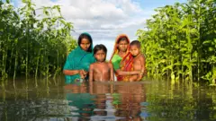 Famille dans les eaux d'inondation au Bangladesh
