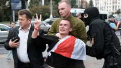 омон задерживает молодого человека, обернутого белорусским флагом
