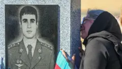 A woman kisses a grave of a Azeri service member killed in a conflict over the region of Nagorno-Karabakh in Baku, Azerbaijan, on 27 September 2021
