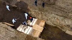 Drone pictures show bodies being buried in a wide trench on New York's Hart Island