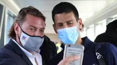 A man takes a selfie with Novak Djokovic as they leave a plane