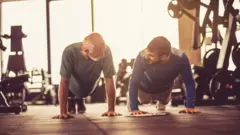 Personal trainer working exercise with senior man at gym.