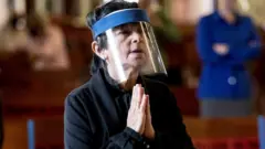 Woman praying in mask in Costa Rica
