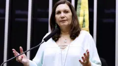 Bia Kicis, uma senhora branca de meia idade com cabelos lisos e castanhos até o ombro, em plenário da Câmara dos Deputados