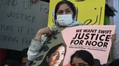 A woman holds a sign saying "justice for Noor"