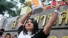 น.ส.จุฑาทิพย์หยิบถังบรรจุสีขาวมาราดใส่ตัวเอง