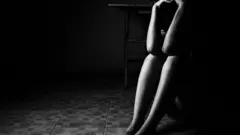 Vulto de mulher sentada com as mãos na cabeça