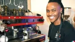 Athenkosi devant une machine à café