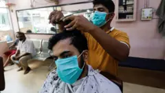 A man wears a protective mask as he has a haircut at a barbershop, after Pakistan lifted lockdown restrictions, as the coronavirus disease (COVID-19) outbreak continues, in Karachi, Pakistan August 10, 2020.