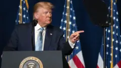 Em parlatório, Trump olha e aponta para o lado