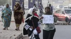 متظاهرتان في الخرطوم تحمل إحداهما لافتة كُتب عليها عبارة تقول "مقتل طالب مقتل أمة".