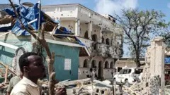 A man stands at the scene of a hotel attack in Somalia