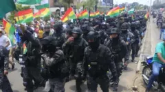 Santa Cruz şehrinde geri çekilen polis memurları Bolivya bayrağını sallıyor