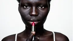 Femme noire qui met du rouge à lèvres