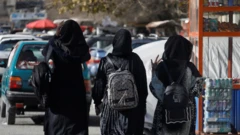 Three female students walking away from university