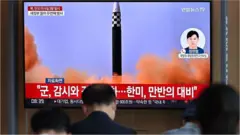 People watch a television screen showing a news broadcast with file footage of a North Korean missile test, at a railway station in Seoul on May 25, 2022, after North Korea fired three ballistic missiles towards the Sea of Japan according to South Korea's military.