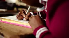 Criança escrevendo em caderno