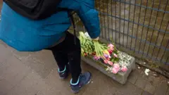 People put down flowers in front of the building where the attack happened
