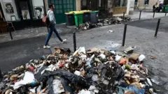 A man walks past a burnt store and damages in a street the day after clashes during protests over French government's pension reform in Paris, France, March 24, 2023.