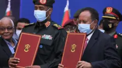 Jenerali Abdel Fattah al-Burhan (ibumoso) na Minisitiri w'intebe Abdalla Hamdok nyuma yo gushyira umukono ku masezerano yo gusaranganya ubutegetsi - ku cyumweru, ku itariki ya 21 y'ukwezi kwa cumi na kumwe mu 2021