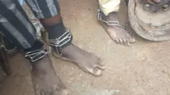 Captives are seen with chains around their ankles as police free them