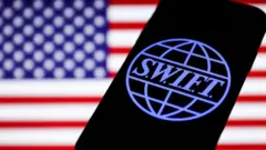 Logotipo SWIFT exibido na tela do telefone e bandeira americana exibida em segundo plano