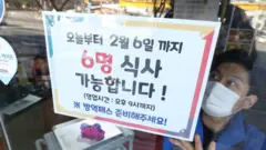 17일 대구 한 음식점 직원이 출입문에 '모임 6인·영업 9시' 거리두기 안내문을 붙이고 있다