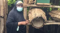 Mama Hadija imbere y'umutiba wa kinyarwanda aho bakorera ubuvumvu