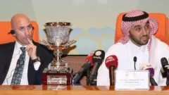 رئيس الاتحاد الملكي الاسباني لكرة القدم لويس روبياليس (يسار) ورئيس الهيئة السعودية العامة للرياضة (الأمير عبد العزيز بن تركي الفيصل) بجوار كأس السوبر الإسباني خلال مؤتمر صحفي في جدة