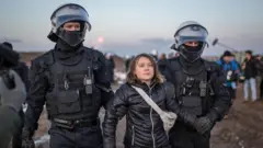 Greta Thunberg flanked by two police officers