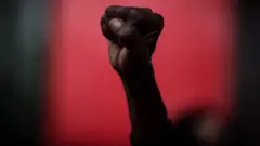 Punho negro fechado sobre fundo vermelho