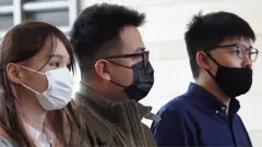 周庭（左）、黃之鋒（右）、林朗彥（中）在香港西九龍法院大樓外（23/11/2020）