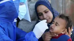 عامل طبي فلسطيني يجري اختبار الكشف عن فيروس كورونا لطفل