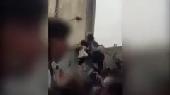 = 阿富汗喀布爾機場外民眾把一名當地女孩遞給看守圍牆的美軍士兵（17/8/2021；Rise to Peace發放視頻截屏）