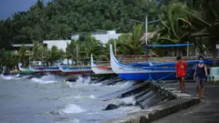 People walk past boats in Legaspi, Albay province, on 31 October 2020