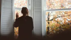 picture of lady looking out of a window