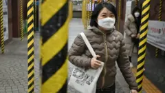 Passengers wearing face masks walk between columns at a subway station being renovated in Seoul