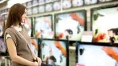 Mujer frente a televisores