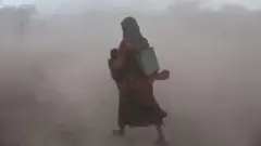 አንድት ሴት ህፃን ይዛ እየተራመደች